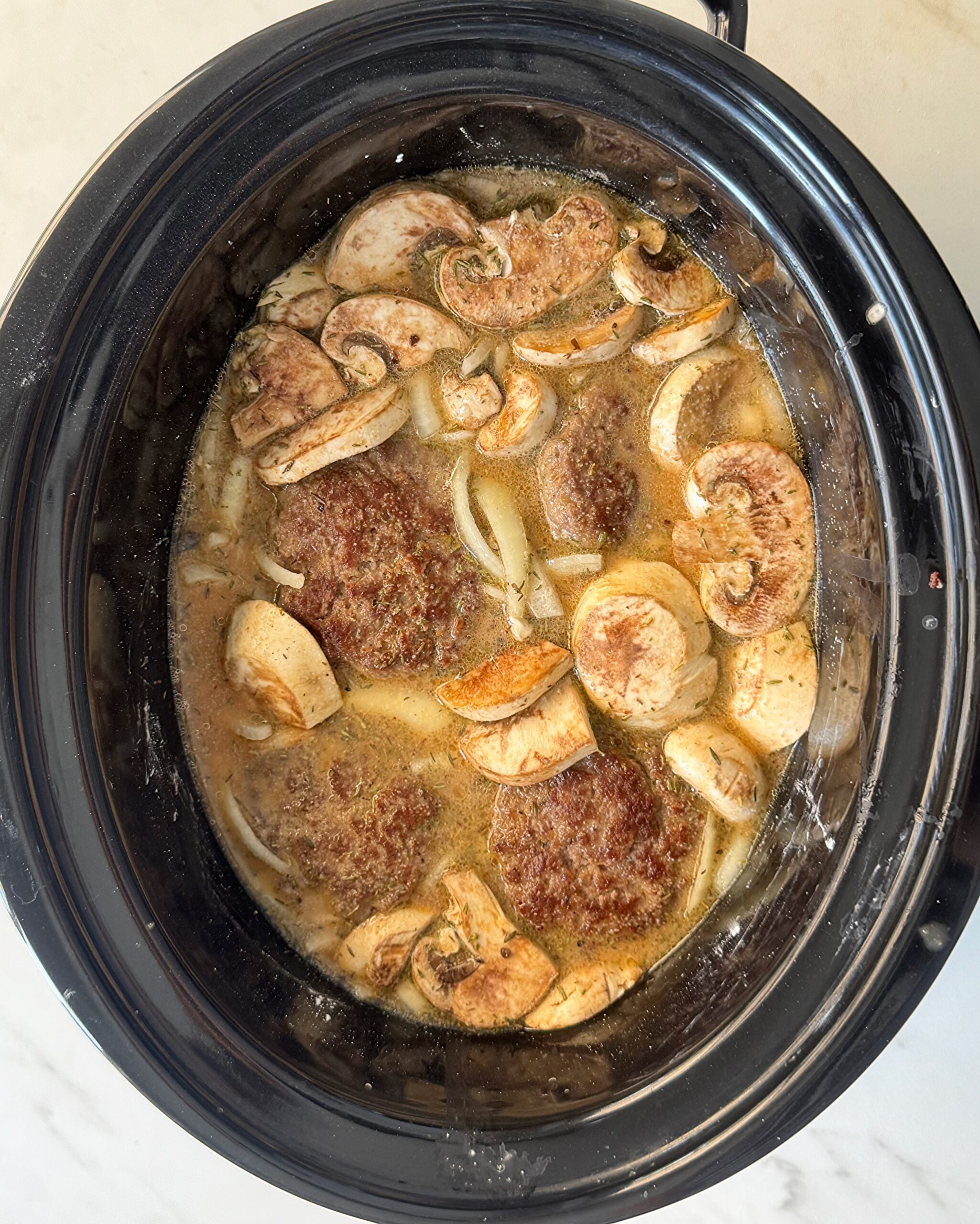 overhead shot of uncooked Salisbury Steak in a black Slow Cooker