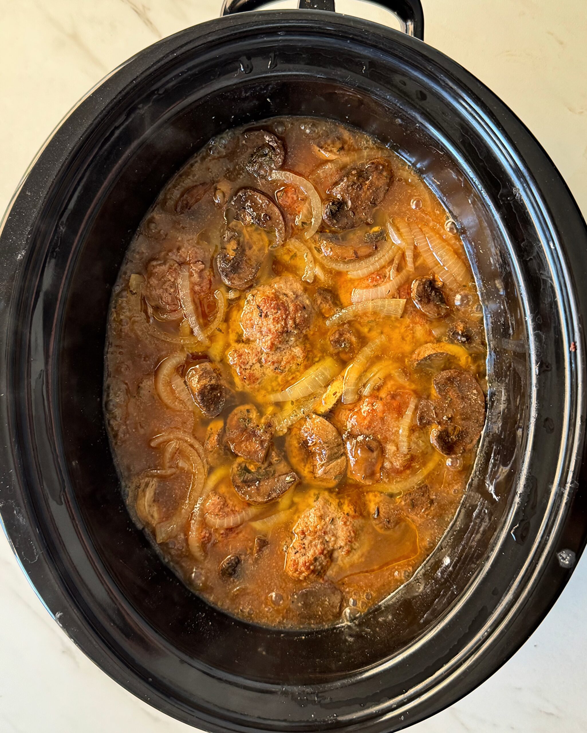 overhead shot of cooked Salisbury Steak in a black Slow Cooker