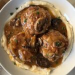 overhead shot of Slow Cooker Salisbury Steak on a white plate served over mashed potatoes